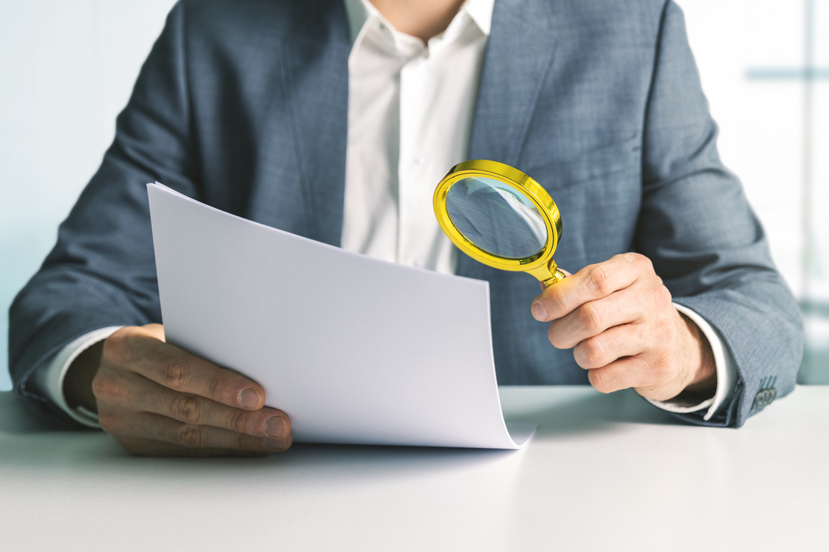 homme avec loupe devant document financier